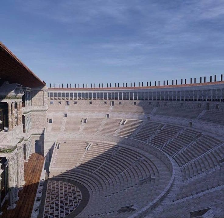 Grande teatro romano antigo com arquibancadas de pedra semicirculares sob um céu azul claro.